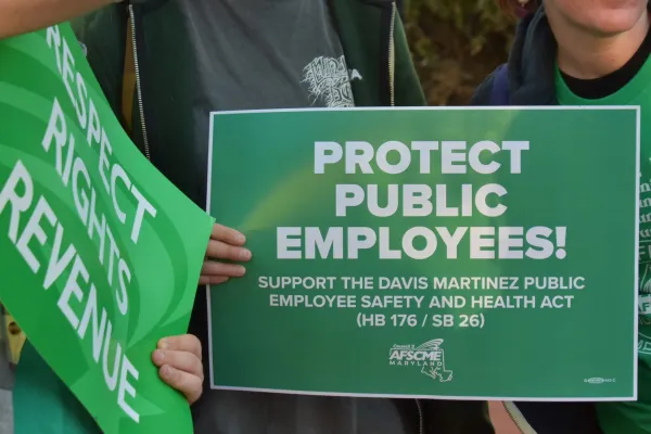 PROTECT PUBLIC EMPLOYEES sign held